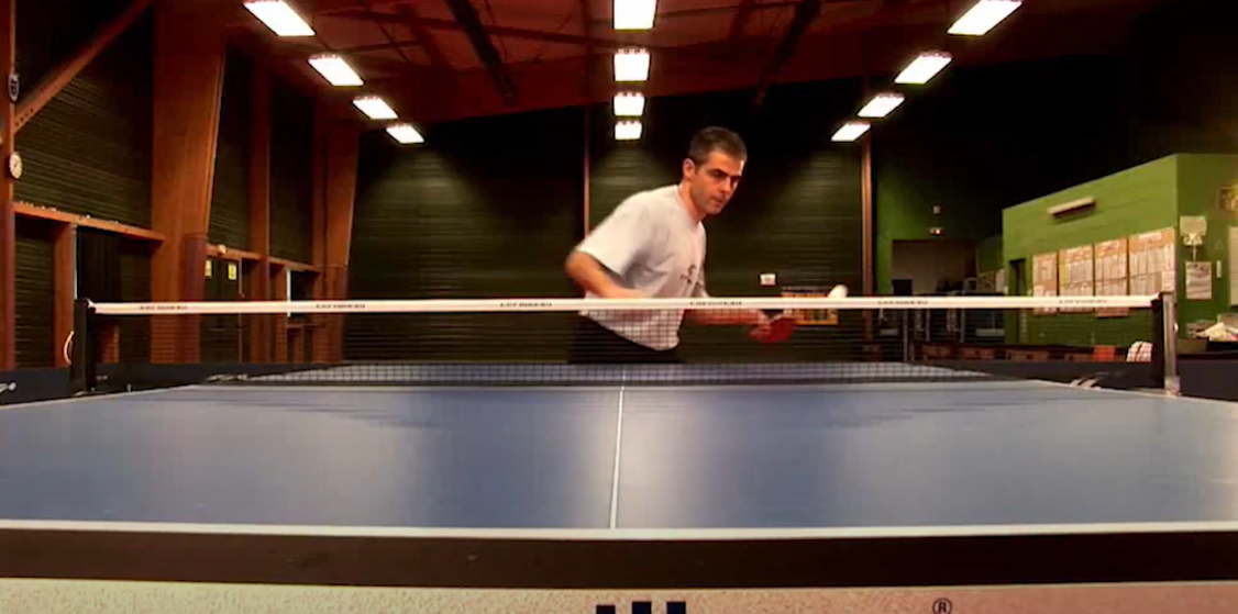 Joueur réalisant un top-spin en compétition sur table Cornilleau